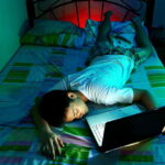 kid lying in bed with a laptop asleep